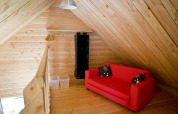 Hippe zolderruimte met houten panelen, rode sofa en opbergruimte in het chalet in Font-Romeu, Frankrijk.