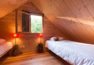 Zwei Einzelbetten in einem gemütlichen Holzdachzimmer im Wooden Chalet in Font-Romeu, Frankreich.