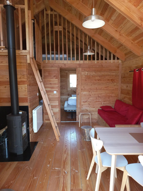 Interiør af Chalet Montana Vista glamping med trægulve, pejs, hems, spisebord og hyggelig stemning.