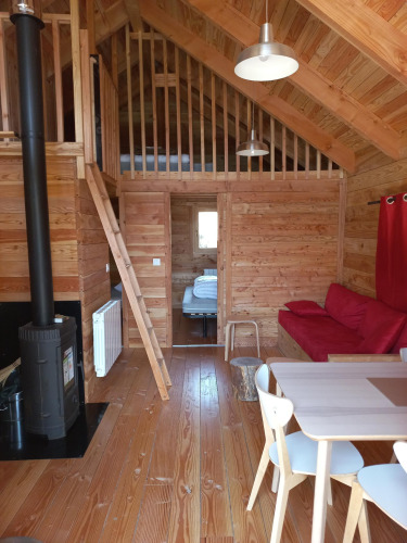 Intérieur du Chalet Montana Vista glamping avec bois, mezzanine, poêle à bois et coin repas convivial.
