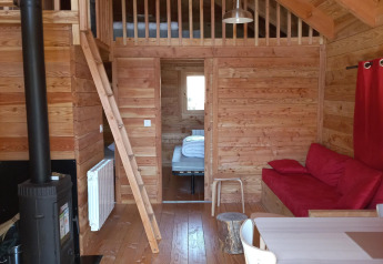 Interno del glamping Chalet Montana Vista con soffitto in legno, stufa, soppalco e zona pranzo.