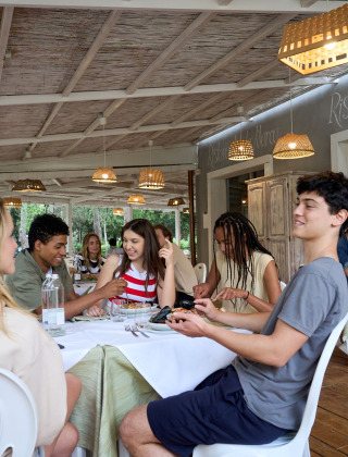 Young adults enjoy a meal together on a covered terrace at Campo dei Fiori, Glamping4all, Tuscany, Italy.