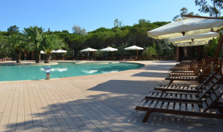 Poolside lounge chairs and umbrellas at Campo dei Fiori Glamping4all holiday park in Tuscany, Italy.