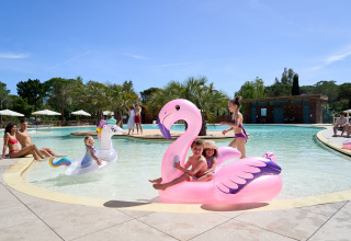 Kinder spielen mit aufblasbaren Flamingos im Pool des Ferienparks Campo dei Fiori in der Toskana, Italien.