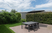 Terraza exterior con mesa negra, cuatro sillas y sombrilla en Access Lodge, Kompas Camping, Westende, Bélgica.