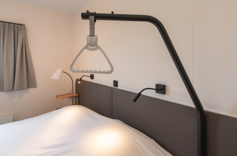 Soveværelse på Access Lodge ved Kompas Camping Westende i Belgien med hjælpelift over sengen.
