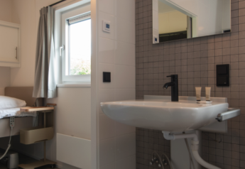 Baño con lavabo y espejo en Access Lodge en Kompas Camping - Westende, Bélgica.