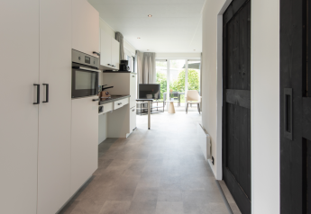 Cocina y sala modernas de casa de campo con grandes ventanales y vista al jardín en Access Lodge, Kompas Camping Westende.