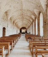 Interior de iglesia con bóvedas, bancos de madera y muros de piedra cerca de Moyaux en Normandía, Francia.