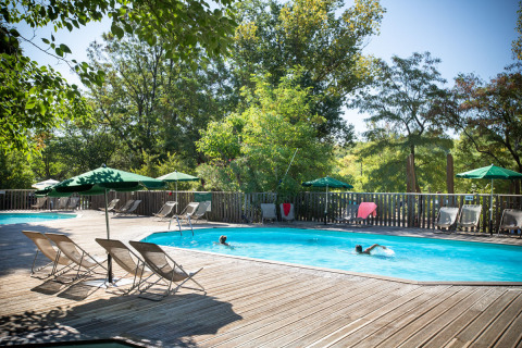 Piscina al aire libre con tumbonas y sombrillas en el parque vacacional Huttopia le Moulin, Auvernia-Ródano-Alpes.