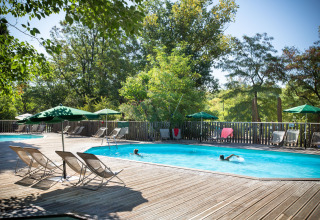 Piscina al aire libre con tumbonas y sombrillas en el parque vacacional Huttopia le Moulin, Auvernia-Ródano-Alpes.