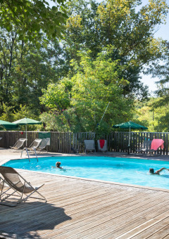 Piscina al aire libre con tumbonas y sombrillas en el parque vacacional Huttopia le Moulin, Auvernia-Ródano-Alpes.