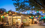 Outdoor seating area with string lights and people dining at Huttopia le Moulin, Auvergne-Rhône-Alpes, France.