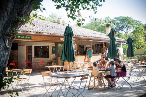 Cafetería al aire libre en Huttopia le Moulin, un parque vacacional en Auvergne-Rhône-Alpes, Francia, con familias.