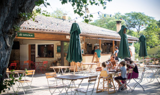 Cafetería al aire libre en Huttopia le Moulin, un parque vacacional en Auvergne-Rhône-Alpes, Francia, con familias.
