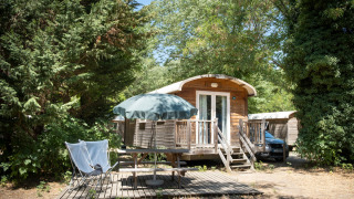 Außenansicht einer Gypsy Caravan-Hütte bei Huttopia le Moulin in Frankreich, von Bäumen umgeben.