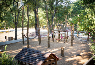 Legeplads med træklatrestativer og rutsjebane i naturpark ved Huttopia le Moulin, Auvergne-Rhône-Alpes, Frankrig.