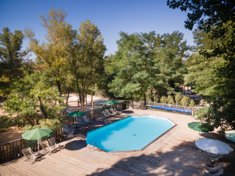 Piscina al aire libre con terraza de madera y tumbonas en el parque vacacional Huttopia le Moulin, Francia.