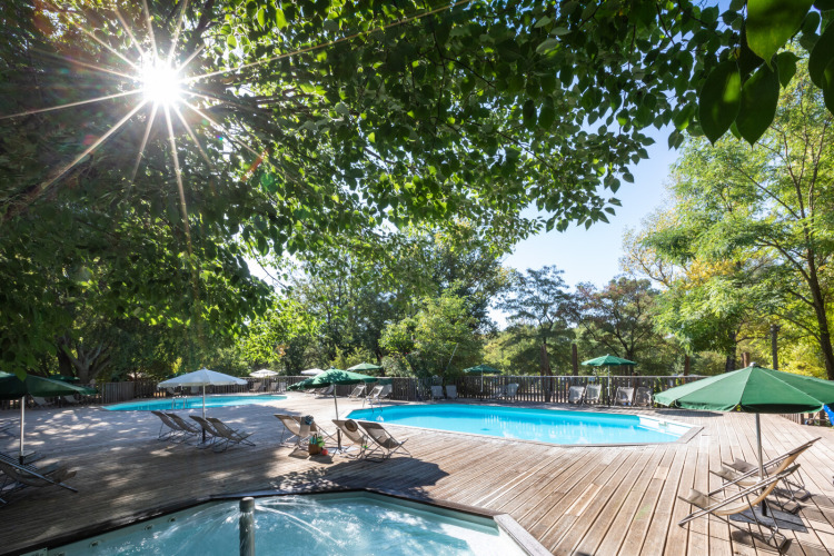 Espace piscine extérieure au Huttopia le Moulin, parc de vacances en Auvergne-Rhône-Alpes, France, entouré d’arbres.