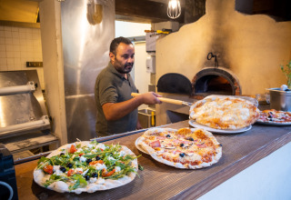 Een kok bakt pizza’s in een houtoven in Huttopia le Moulin, een vakantiedomein in Auvergne-Rhône-Alpes, Frankrijk.