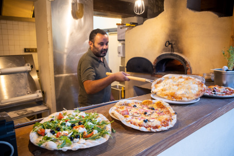 Un chef prépare des pizzas au four à bois à Huttopia le Moulin, un parc de vacances en Auvergne-Rhône-Alpes, France.