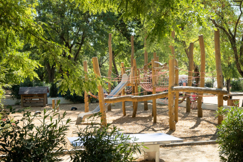 Parque infantil de madera con tobogán y cuerdas de escalar en Huttopia le Moulin, Auvergne-Rhône-Alpes, Francia.