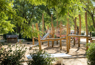 Houten speeltuin met glijbaan en klimnetten bij Huttopia le Moulin vakantiepark in Auvergne-Rhône-Alpes, Frankrijk.