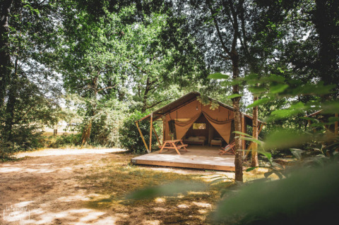 Tienda safari entre árboles en el Huttopia Vallée du Lot, parque vacacional de Nouvelle-Aquitaine, Francia.