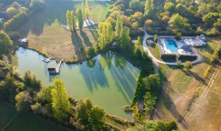 Vista aérea de un lago verde, piscina y árboles cerca de St. Étienne-de-Villeréal, Nouvelle-Aquitaine, Francia.