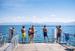 Ragazzi e bambini si rilassano su un molo sul lago a Huttopia Divonne Les Bains in Auvergne-Rhône-Alpes, Francia.