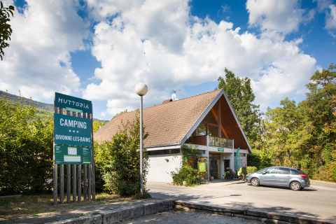 Ingresso del campeggio Huttopia Divonne Les Bains in Auvergne-Rhône-Alpes, Francia con cielo sereno.