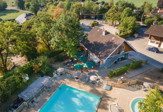 Luftfoto af Huttopia Divonne Les Bains feriepark i Auvergne-Rhône-Alpes med pool og grønne omgivelser.
