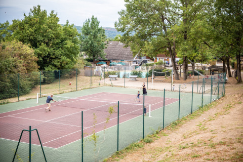 Persone che giocano a tennis su un campo all'aperto al villaggio Huttopia Divonne Les Bains, Francia.