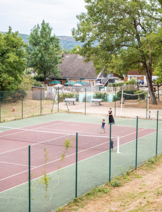 Menschen spielen Tennis auf einem Außenplatz im Ferienpark Huttopia Divonne Les Bains in Frankreich.