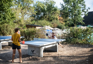 Twee personen spelen buiten tafeltennis op het vakantiepark Huttopia Divonne Les Bains in Auvergne-Rhône-Alpes.