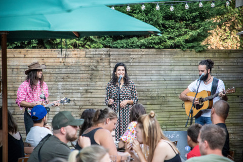 Músicos actúan en el exterior mientras la gente cena en Huttopia Divonne Les Bains, parque de vacaciones.