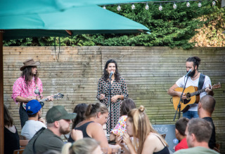 Muzikanten geven een openluchtoptreden terwijl gasten dineren in Huttopia Divonne Les Bains vakantiepark.