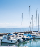 Barcos atracados cerca de Divonne Les Bains, Francia, con personas en el embarcadero y montañas al fondo.