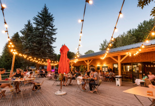 Gezellige avonddiners onder lichtjes bij Huttopia Lac de la Siauve vakantiepark in Auvergne, Frankrijk.