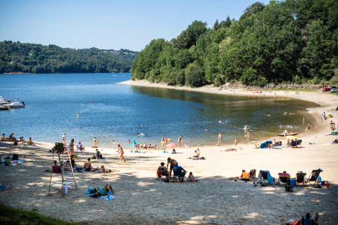 Feriepark strand ved Huttopia Lac de la Siauve i Auvergne-Rhône-Alpes, Frankrig, med folk der nyder solen.
