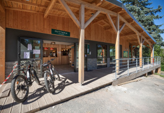 Ingang van Huttopia Lac de la Siauve, vakantiepark in Auvergne-Rhône-Alpes, met fietsen aan houten gebouw.