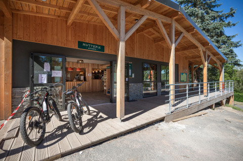 Entrée de Huttopia Lac de la Siauve, parc de vacances en Auvergne-Rhône-Alpes, avec vélos devant le bâtiment en bois.