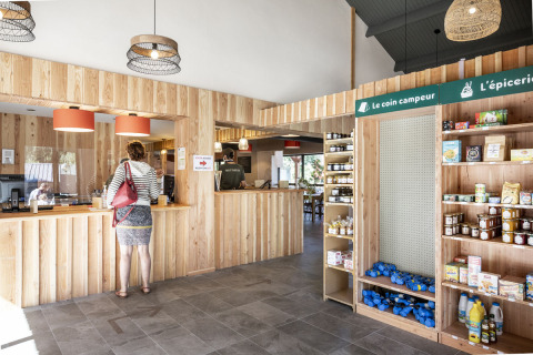 Recepción y pequeña tienda con interior de madera en Huttopia Lac de la Siauve, parque vacacional de Auvergne-Rhône-Alpes, Francia.
