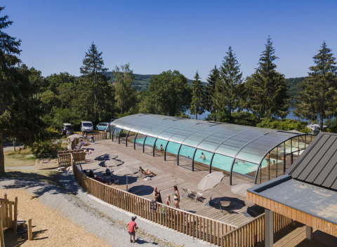 Piscina al aire libre con cubierta de vidrio y terraza en Huttopia Lac de la Siauve, Auvergne-Rhône-Alpes, Francia.