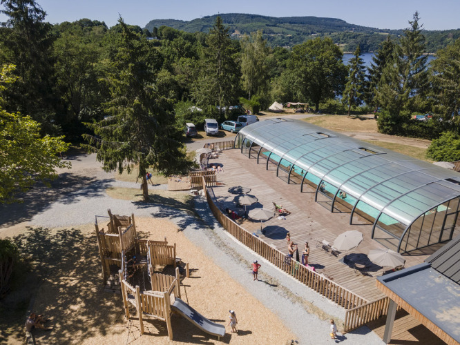 Playground and covered swimming pool at Huttopia Lac de la Siauve holiday park in Auvergne-Rhône-Alpes, France.