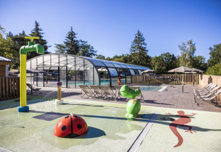 Espace piscine extérieur avec transats, jeux et bassin couvert à Huttopia Lac de la Siauve, en France.
