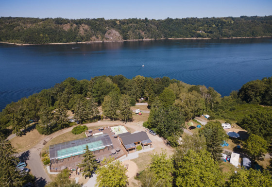 Luchtbeeld van het vakantiepark Huttopia Lac de la Siauve in Auvergne-Rhône-Alpes met bos, zwembad en meer.