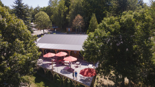 Vista de una terraza con sombrillas rojas entre árboles en Huttopia Lac de la Siauve, un parque en Francia.