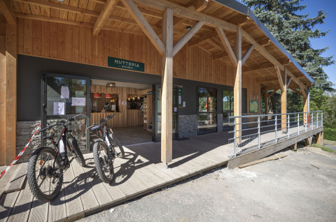 Entrée de Huttopia Lac de la Siauve avec terrasse en bois, vélos à louer et accueil en Auvergne-Rhône-Alpes.
