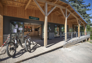 Ingang van Huttopia Lac de la Siauve met houten terras, huurfietsen en onthaal in Auvergne-Rhône-Alpes.
